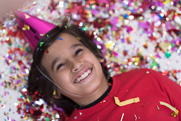 Image showing kid blowing confetti while lying on the floor