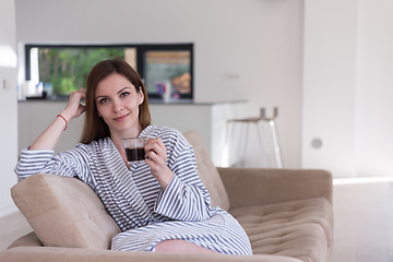 Image showing young woman in a bathrobe enjoying morning coffee