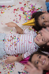 Image showing kids  blowing confetti while lying on the floor