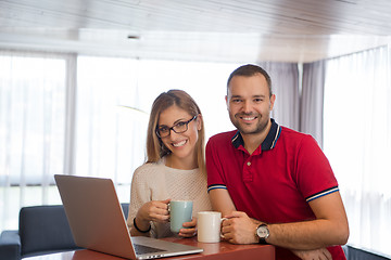 Image showing couple drinking coffee and using laptop at home