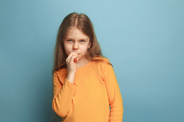 Image showing The thoughtful girl. Teen girl on a blue background. Facial expressions and people emotions concept