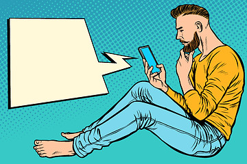 Image showing Hipster man sitting on the floor and reading smartphone