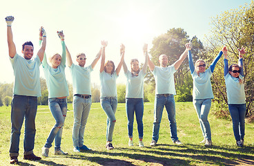 Image showing group of happy volunteers holding hands outdoors