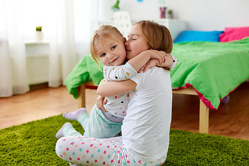 Image showing happy little girls or sisters hugging at home