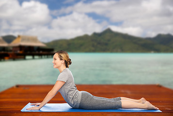 Image showing woman making yoga in dog pose on mat outdoors