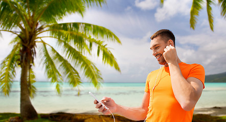 Image showing man with smartphone and earphones over beach