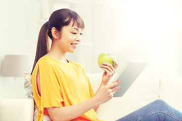 Image showing happy asian woman with tablet pc and apple at home