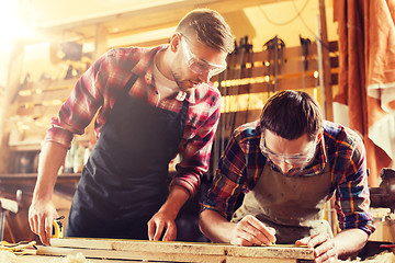 Image showing carpenters with ruler and wood plank at workshop