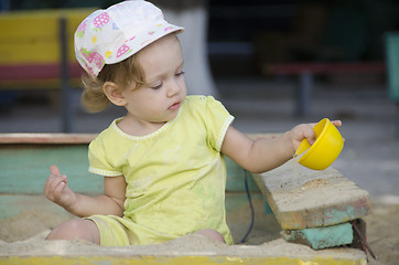 Image showing Little girl is playing in the old sandbox