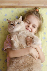 Image showing The girl closed her eyes with joy, hugging her pet cat