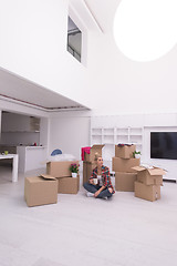 Image showing woman with many cardboard boxes sitting on floor