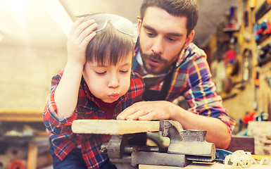 Image showing father and little son with wood plank at workshop