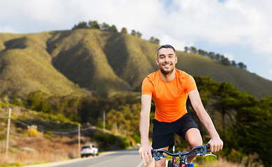 Image showing happy young man riding bicycle over big sur hills