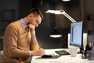 Image showing man with notepad working on code at night office