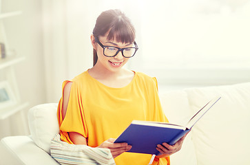 Image showing smiling young asian woman reading book at home