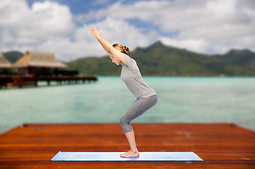 Image showing woman making yoga in chair pose on mat outdoors