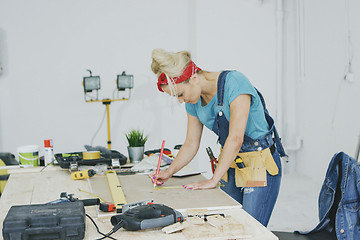 Image showing Female carpenter drawing lines on plywood sheet 