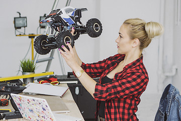 Image showing Woman examining radio-controlled car in workshop