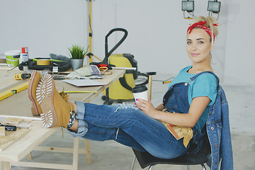 Image showing Female relaxing at carpenter workbench with drink 