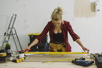 Image showing Woman measuring plywood sheet with spirit level 
