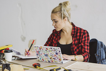 Image showing Female with laptop writing in notebook 