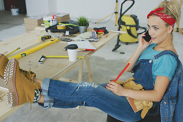 Image showing Female carpenter at workplace talking on smartphone 