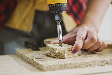 Image showing Woman driving screw into chipboard with gun