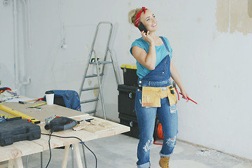 Image showing Cheerful female carpenter talking on smartphone 