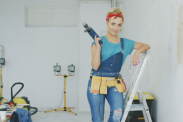 Image showing Woman with drill standing on stepladder 