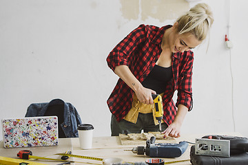 Image showing Female drilling wooden plank on workbench 