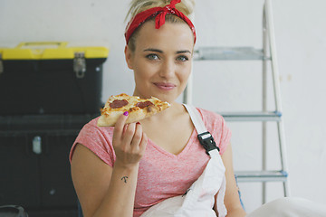 Image showing Smiling woman in overalls eating tasty pizza