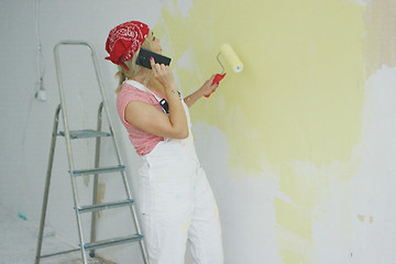 Image showing Painting wall woman talking on smartphone 