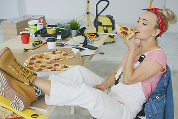 Image showing Female carpenter eating pizza at workplace