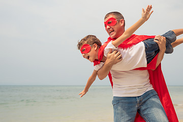 Image showing Father and son playing superhero on the beach at the day time.