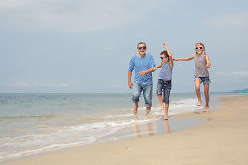 Image showing Father and children  playing on the beach at the day time.