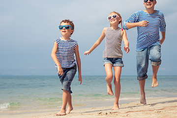 Image showing Father and kids running on the beach at the day time. 