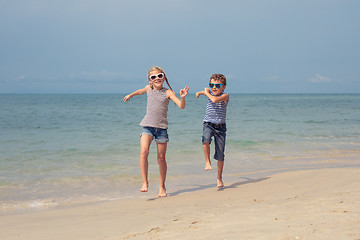 Image showing Two happy little children playing on the beach at the day time. 