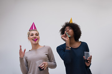 Image showing smiling women in party caps blowing to whistles