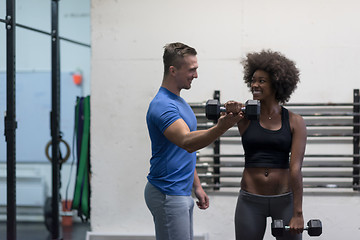 Image showing black woman doing bicep curls with fitness trainer