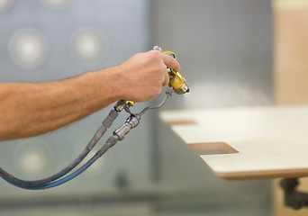 Image showing worker hand sprays urethane finish to board