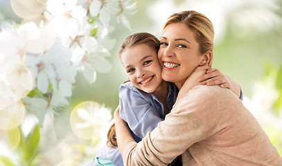 Image showing happy mother hugging daughter over cherry blossom