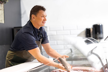 Image showing male seller showing seafood at fish shop fridge