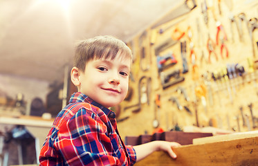 Image showing happy little boy with wood plank at workshop