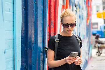 Image showing Woman using smartphone against colorful graffiti wall in New York city, USA.