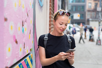 Image showing Woman using smartphone against colorful graffiti wall in New York city, USA.