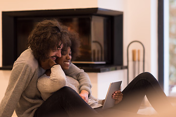 Image showing multiethnic couple using tablet computer on the floor