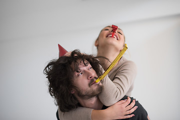 Image showing couple in party hats blowing in whistle