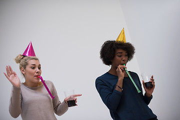 Image showing smiling women in party caps blowing to whistles