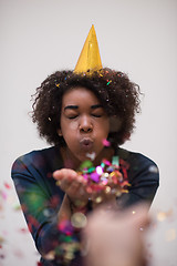 Image showing African American woman blowing confetti in the air