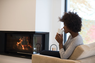 Image showing black woman drinking coffee in front of fireplace